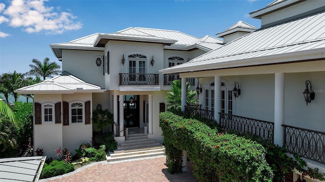 1435 Westway Dr, Sarasota, FL 34236 - view of front of home with a standing seam roof, a metal roof, a balcony, stucco siding, and french doors