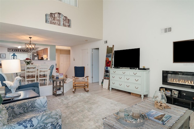 3609 57th Avenue Dr W Unit 37, Bradenton, FL 34210 - living room with a chandelier, light wood-type flooring, a towering ceiling, and a glass covered fireplace