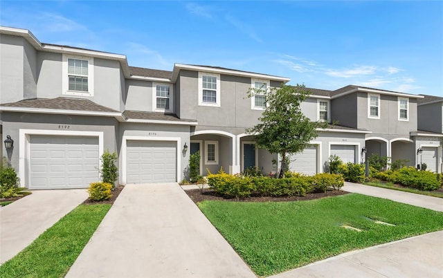 8596 Lunar Skye St, Sarasota, FL 34241 - townhome / multi-family property with a front yard, an attached garage, concrete driveway, and stucco siding