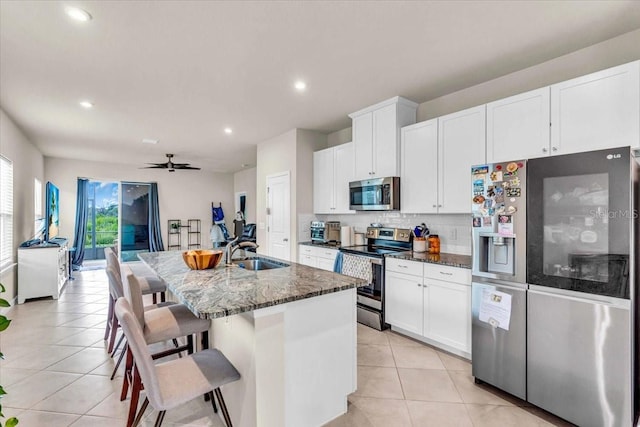 10616 High Noon Trl, Parrish, FL 34219 - kitchen with a center island with sink, a sink, dark stone countertops, appliances with stainless steel finishes, and light tile patterned floors