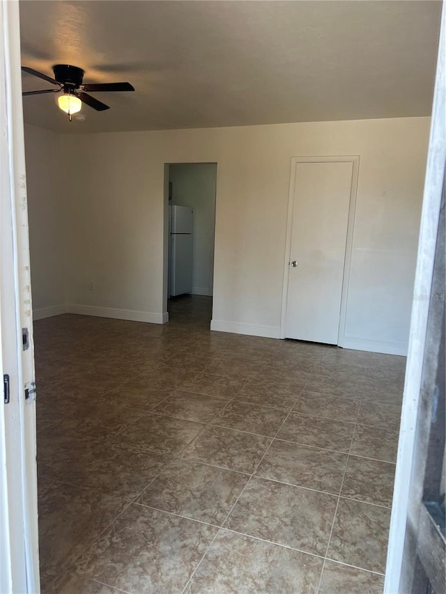 unfurnished room with a ceiling fan and baseboards