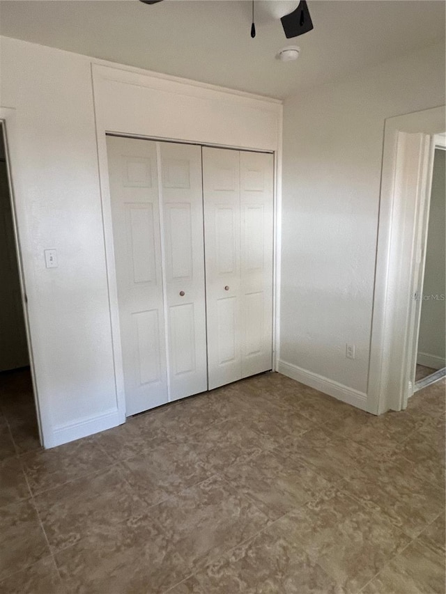 unfurnished bedroom featuring baseboards, tile patterned floors, and a closet