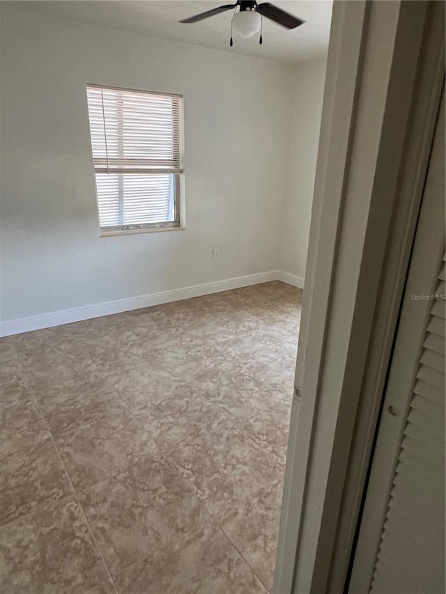 spare room featuring a ceiling fan and baseboards