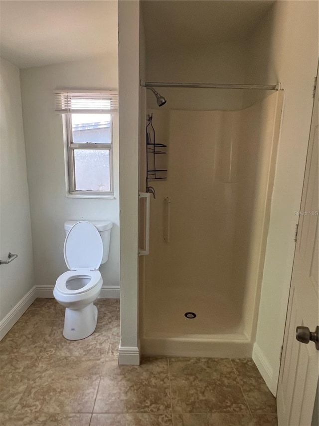 full bathroom featuring baseboards, a shower stall, and toilet