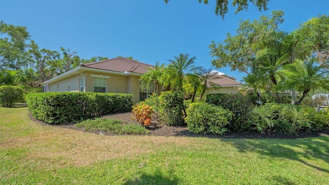 5355 Anthony Ln, Sarasota, FL 34233 - view of side of home with a lawn, stucco siding, and a tiled roof