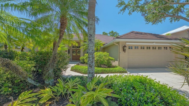 5355 Anthony Ln, Sarasota, FL 34233 - view of front of house with a tiled roof, driveway, a garage, and stucco siding
