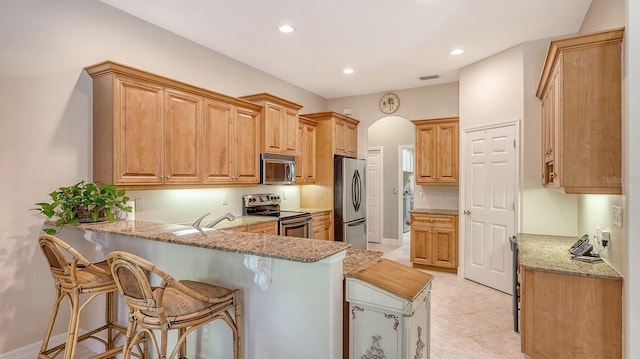 5355 Anthony Ln, Sarasota, FL 34233 - kitchen with appliances with stainless steel finishes, a peninsula, light stone countertops, and recessed lighting