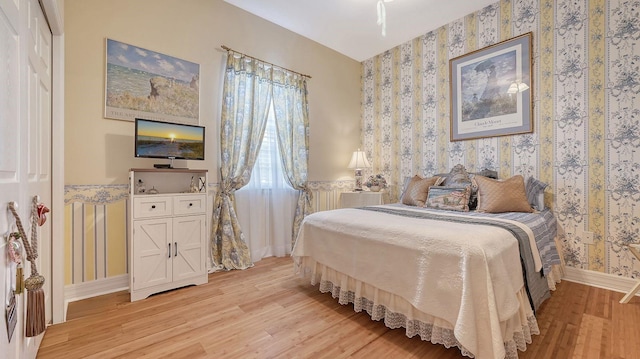 5355 Anthony Ln, Sarasota, FL 34233 - bedroom featuring wallpapered walls, light wood finished floors, and baseboards