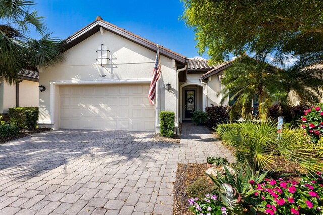 2397 Vaccaro Dr, Sarasota, FL 34231 - mediterranean / spanish-style house with a garage, stucco siding, decorative driveway, and a tiled roof