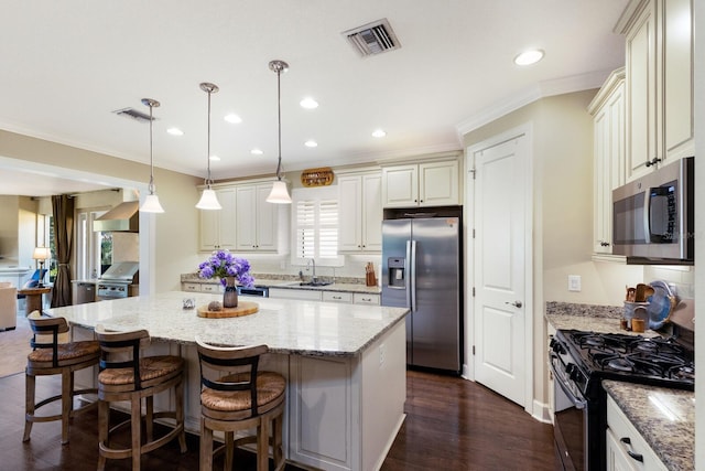 2397 Vaccaro Dr, Sarasota, FL 34231 - kitchen featuring appliances with stainless steel finishes, crown molding, light stone countertops, a sink, and a kitchen island