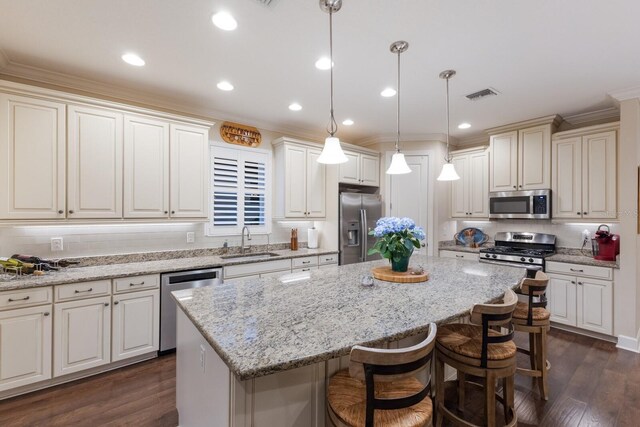 2397 Vaccaro Dr, Sarasota, FL 34231 - kitchen featuring stainless steel appliances, a sink, a kitchen island, a breakfast bar area, and dark wood-style flooring