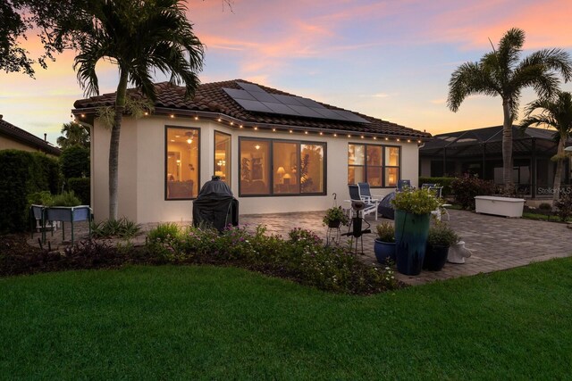 2397 Vaccaro Dr, Sarasota, FL 34231 - rear view of property with a patio area, a lawn, roof mounted solar panels, and stucco siding