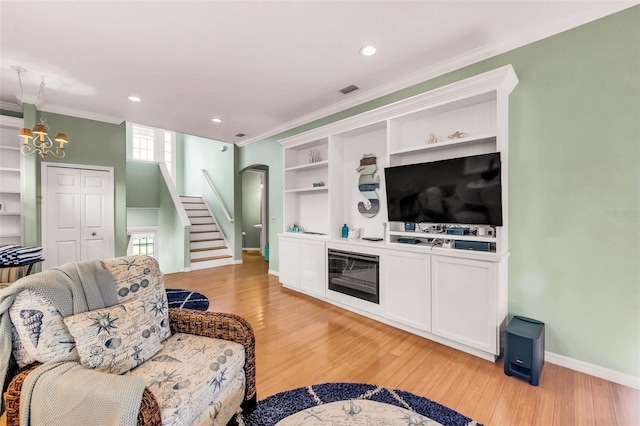 426 Magnolia Ave, Anna Maria, FL 34216 - living room with stairway, ornamental molding, a notable chandelier, and light wood-style floors