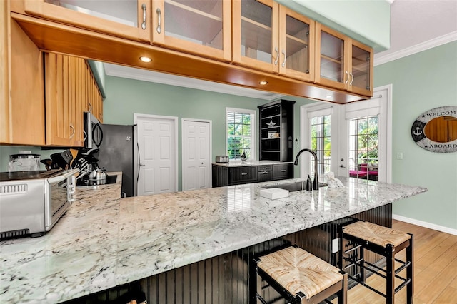 426 Magnolia Ave, Anna Maria, FL 34216 - kitchen featuring ornamental molding, a sink, stainless steel microwave, light wood-style floors, and a peninsula