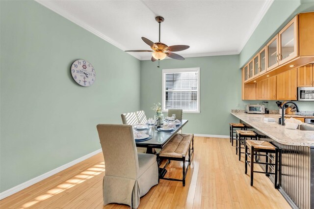 426 Magnolia Ave, Anna Maria, FL 34216 - dining room featuring baseboards, light wood-style floors, ceiling fan, and crown molding