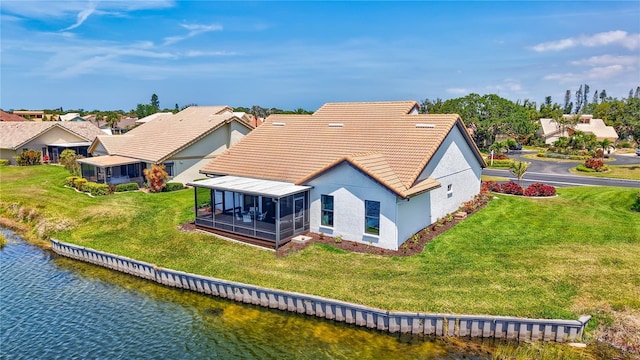 75 Inlets Blvd Unit 75, Nokomis, FL 34275 - back of house featuring a lawn, a water view, a tiled roof, stucco siding, and a sunroom
