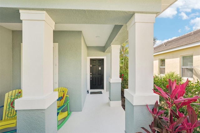 entrance to property featuring stucco siding and covered porch