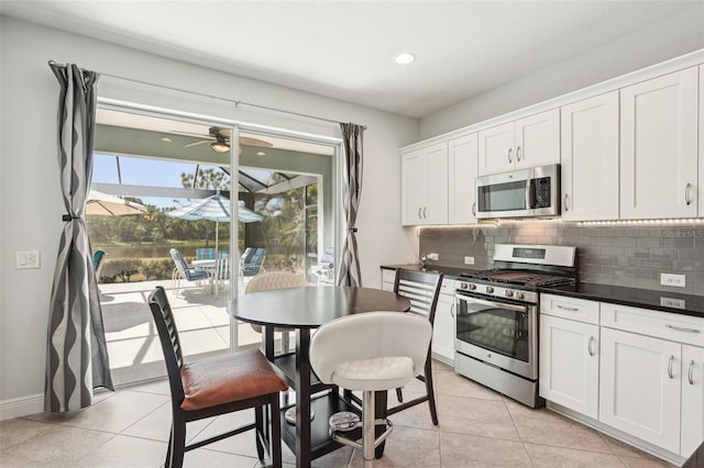 kitchen with light tile patterned flooring, appliances with stainless steel finishes, decorative backsplash, and white cabinetry
