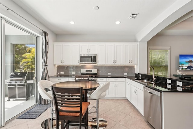 kitchen with a sink, stainless steel appliances, tasteful backsplash, visible vents, and a peninsula