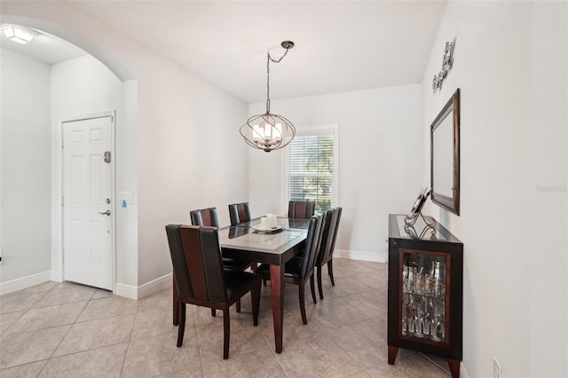 dining space with light tile patterned floors, a chandelier, baseboards, and arched walkways