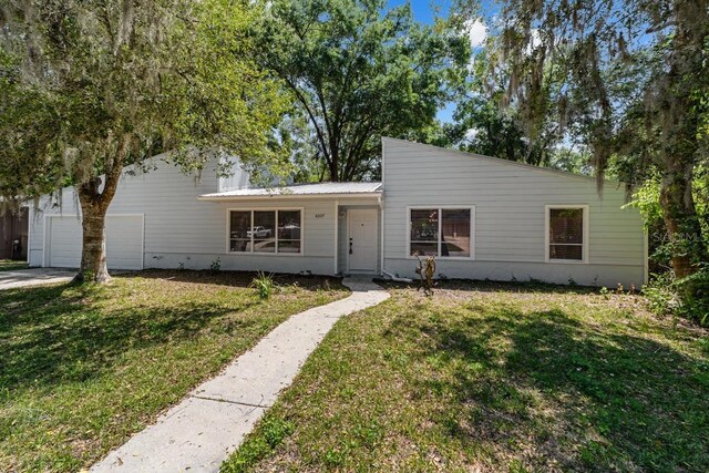 view of front of home featuring an attached garage, a front lawn, and metal roof