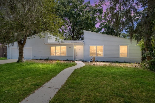 view of front of property with concrete driveway, a front lawn, and an attached garage