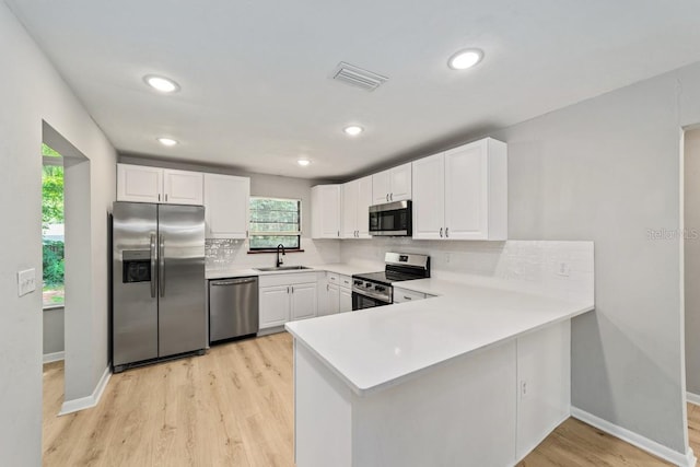 kitchen with stainless steel appliances, a sink, visible vents, backsplash, and white cabinetry