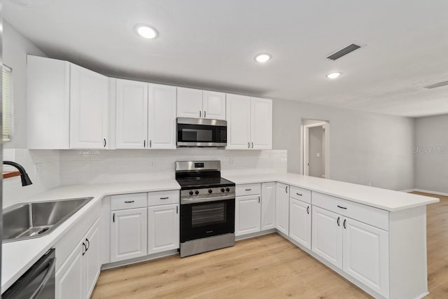 kitchen featuring stainless steel appliances, a peninsula, a sink, visible vents, and light countertops