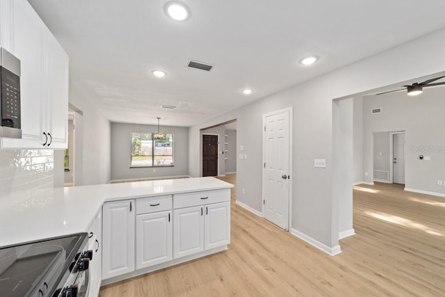 kitchen with white cabinets, visible vents, light wood-type flooring, a peninsula, and stainless steel electric stove