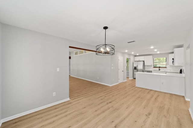 unfurnished living room featuring recessed lighting, light wood-type flooring, and baseboards