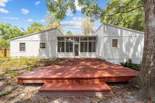 rear view of property with fence, a wooden deck, and a sunroom