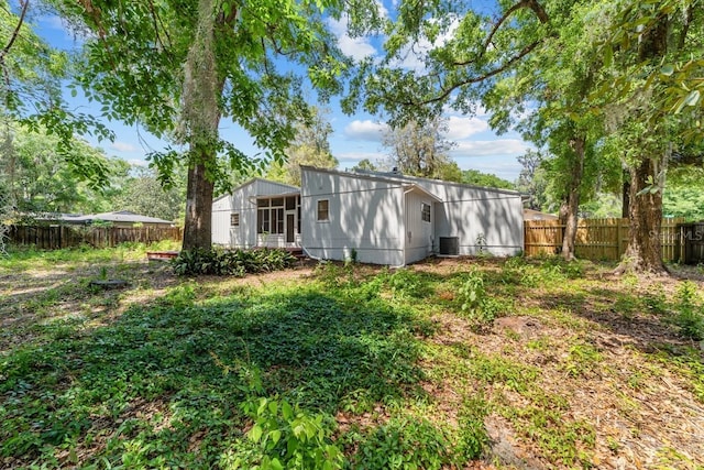 rear view of property featuring a fenced backyard, a sunroom, and cooling unit