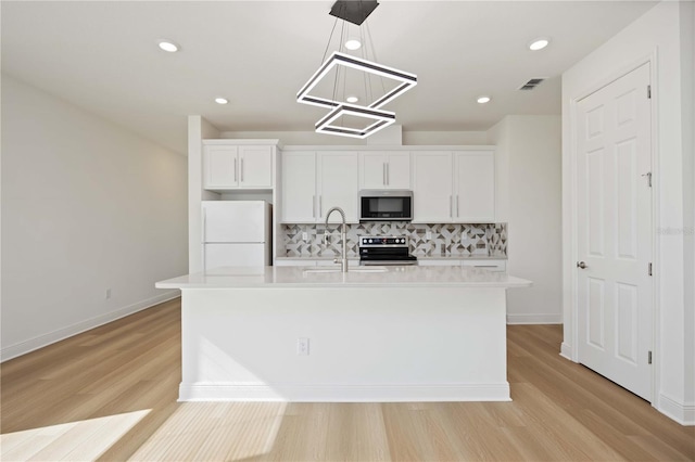 kitchen featuring backsplash, appliances with stainless steel finishes, light wood-type flooring, light countertops, and a chandelier