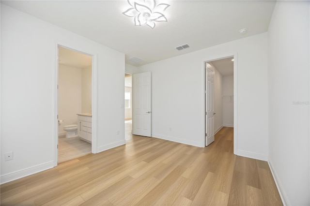 10455 Wet Marsh Cv, Parrish, FL 34219 - unfurnished bedroom featuring light wood-style floors, a spacious closet, baseboards, and connected bathroom