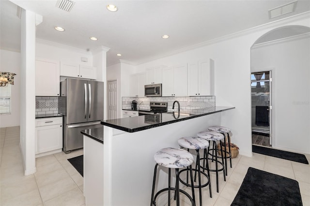 9101 Yarberry St, Sarasota, FL 34240 - kitchen featuring appliances with stainless steel finishes, a breakfast bar, a peninsula, light tile patterned floors, and ornamental molding