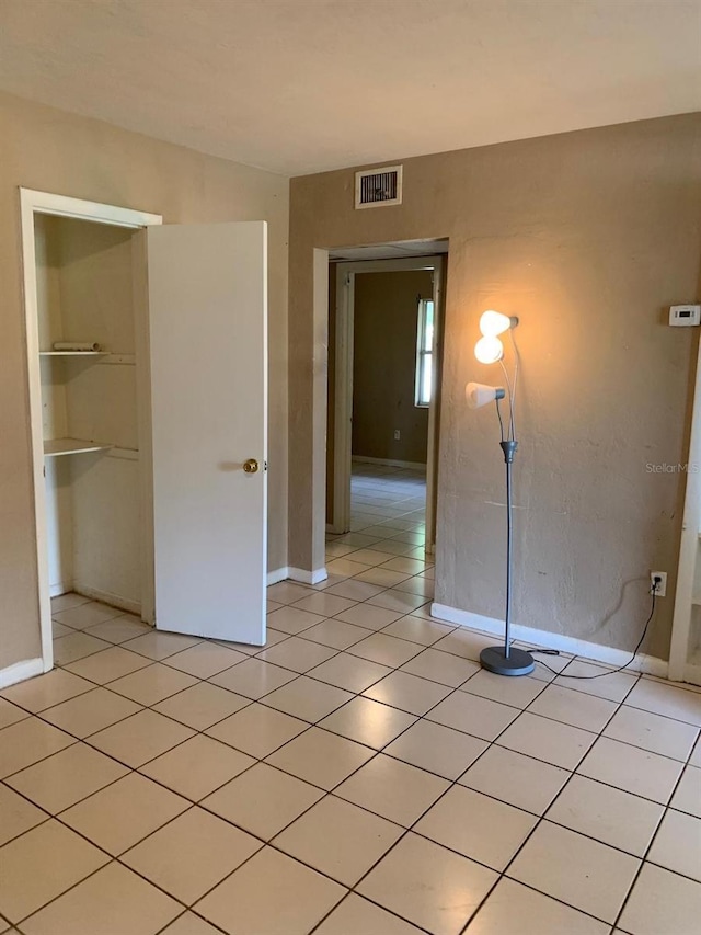 unfurnished bedroom with baseboards, visible vents, a closet, and light tile patterned floors