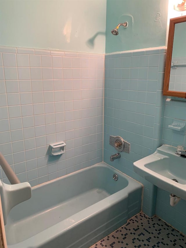 bathroom with tile patterned flooring, tub / shower combination, tile walls, and a wainscoted wall