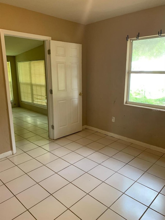 spare room with baseboards and light tile patterned floors