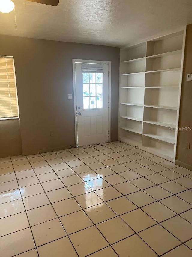 21291 Coulton Ave, Port Charlotte, FL 33952 - doorway to outside with light tile patterned flooring, a textured ceiling, a ceiling fan, and built in features