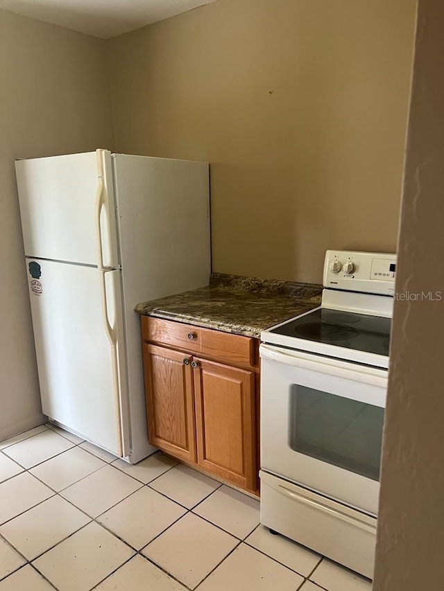 21291 Coulton Ave, Port Charlotte, FL 33952 - kitchen featuring white appliances, light tile patterned floors, and brown cabinetry