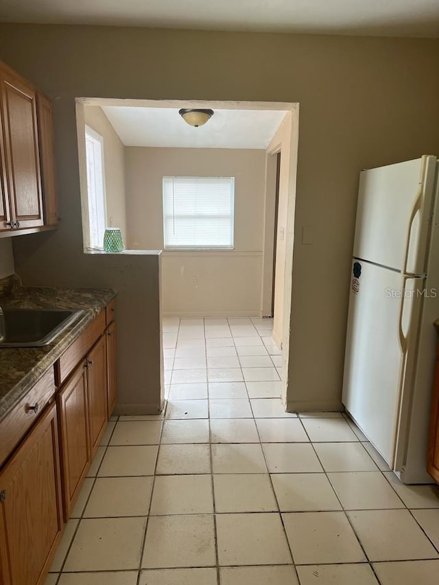 21291 Coulton Ave, Port Charlotte, FL 33952 - kitchen featuring freestanding refrigerator, dark countertops, brown cabinets, and light tile patterned floors