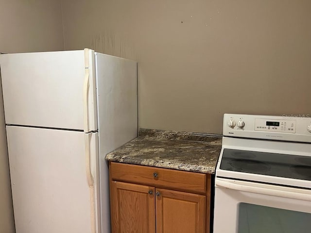 21291 Coulton Ave, Port Charlotte, FL 33952 - kitchen with white appliances, dark stone counters, and brown cabinets