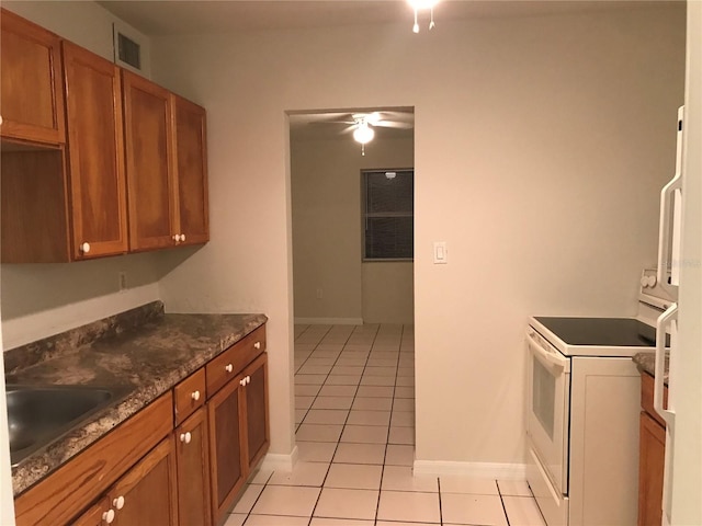 21291 Coulton Ave, Port Charlotte, FL 33952 - kitchen featuring white electric stove, light tile patterned floors, brown cabinets, and ceiling fan