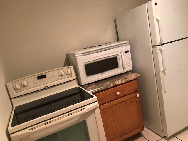 21291 Coulton Ave, Port Charlotte, FL 33952 - kitchen featuring white appliances, brown cabinetry, dark countertops, and light tile patterned floors