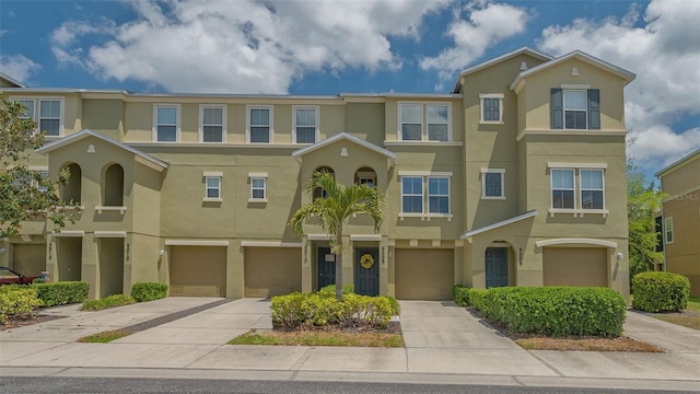townhome / multi-family property featuring stucco siding, an attached garage, and driveway