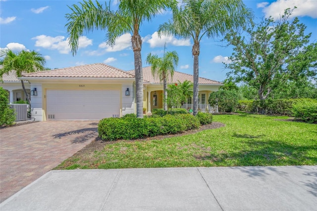 5821 Valente Pl, Sarasota, FL 34238 - view of front facade featuring stucco siding, decorative driveway, central air condition unit, a front yard, and an attached garage