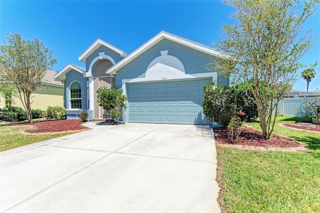 ranch-style home featuring a front lawn, concrete driveway, fence, a garage, and stucco siding