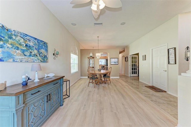 dining room with visible vents, light wood finished floors, baseboards, and ceiling fan with notable chandelier