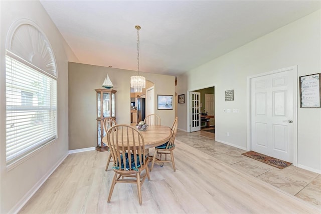 dining space with baseboards, french doors, and a chandelier