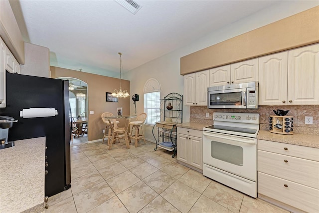 kitchen featuring stainless steel appliances, an inviting chandelier, decorative backsplash, light countertops, and light tile patterned floors